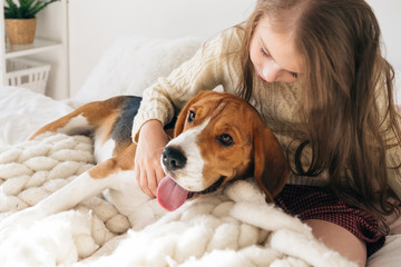 Little girl with dog lying on bed and laughing