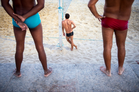 Unrecognizable young men stand on the beach in sunga, a local style of swimwear popular in Rio de Janeiro, Brazil