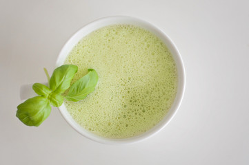 Healthy green tea matcha latte with soy and oat milk in a white tea cup decorated with basil and foam on top - a warm beverage to boost brain function and as a cancer prevention!