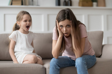 Stressed mother feeling desperate about screaming stubborn kid daughter tantrum - obrazy, fototapety, plakaty