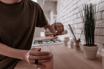 Close up of woman adding some liquor to her morning tea