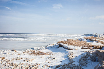 Frozen Coast. Sunny winter landscape. Extreme tourism and ice fishing