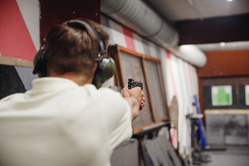 Fototapeta na wymiar Man directs firearm gun pistol at target firing range or shooting range