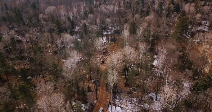 Aerial shot. A logging truck loaded with freshly sawn timber leaves the logging site in the taiga. Long wagon with sawn wood loaded into the body