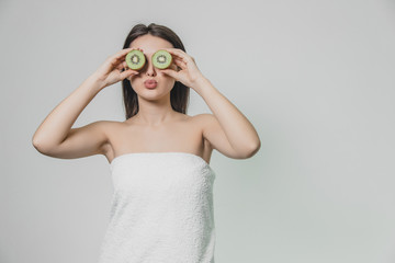 Young pretty girl standing on a white background. During this, at the level of the eye, the kivia particles are held in the hands of the eyes with their eyes closed.