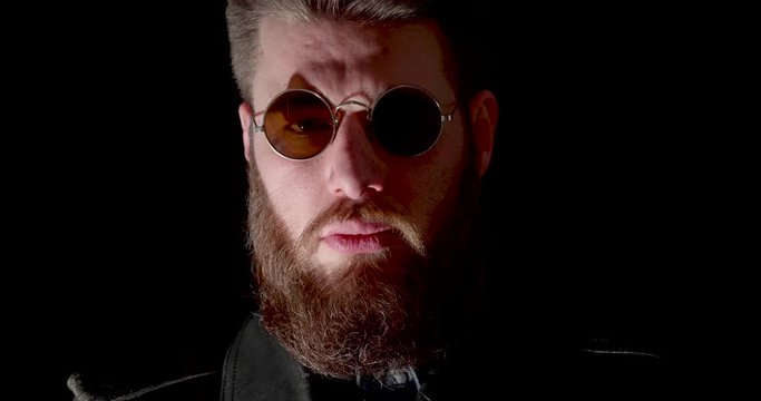 Dangerous man with beard with lights changing on his face. Lights moving on the face of a rocker.