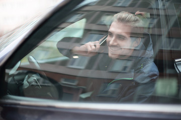 young man talking on mobile phone in the car