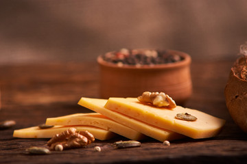 Peppercorns in a wooden bowl on table with cheese. Homemade food