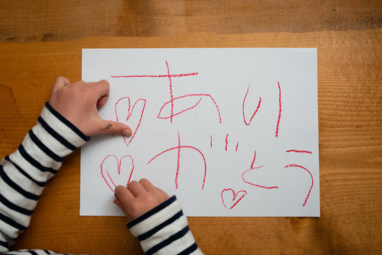 紙にありがとうと書く子供