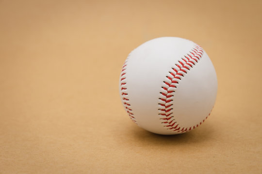 Isolated baseball on a brown background and red stitching baseball. White baseball with red thread.Baseball is a national sport of Japan. It is popular.