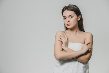 Fototapeta premium Beautiful young girl with smooth skin on a light background with natural make-up and curly dark hair.