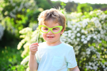 Small child with summer party glasses. Childhood happiness. Childrens day. Little boy child in green forest. spring holiday. Sunny weather. Happy kid in blooming nature. Spring collection