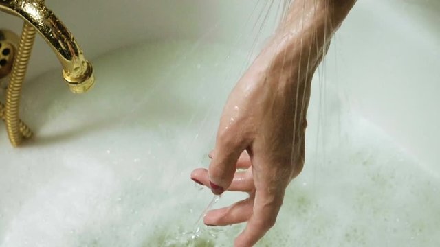 The woman filling the bathtub with water and women's hand trying water. Slow motion. HD