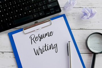 Top view of magnifying glass,trash paper,keyboard,pen,clipboard and paper written with Resume...