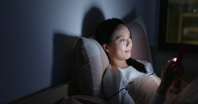 Woman use of mobile phone and lying down on bed at night
