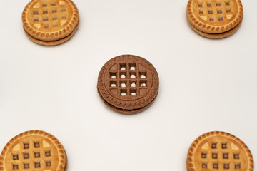 Vanilla and chocolate cookies on a white background, chocolate one in the center. Perspective