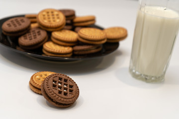 Close-up of chocolate and vanilla cookies and a glass of milk on white table