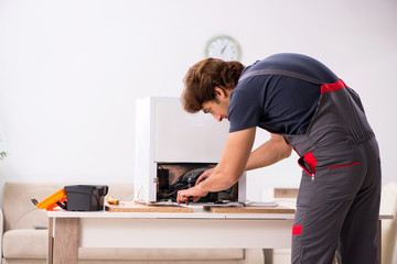 Young handsome contractor repairing fridge 