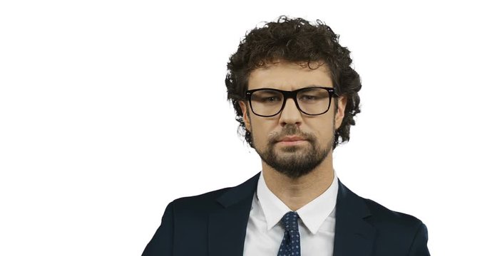 Close up of the attractive serious businessman in suit and tie fixing his glasses and looking straight to the camera on the white screen background. Portrait.