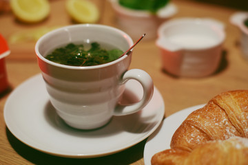 Green tea with mint and croissants on a wooden table. Empty copy space