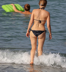 Fototapeta premium Girl in a swimsuit on the beach of the sea