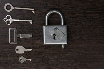 a lot of keys lie next to the lock on a wooden background