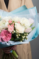 lush bouquet of fresh flowers in a beautiful wrapper in female hands with a neat manicure