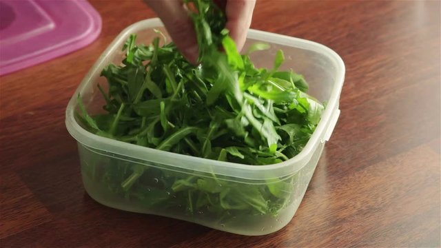 man open food container with fresh arugula leaves 
