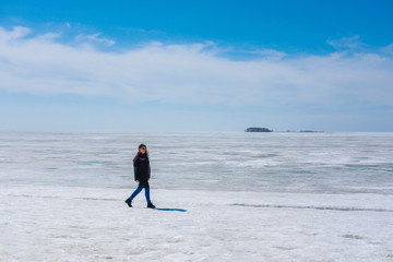 Woman enjoying the view of the snowy sea. Winter spring fashion.
