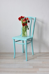 vintage turquoise chair with a bouquet of pink tulips in a glass vase
