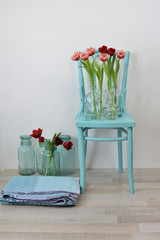 vintage turquoise chair with pink tulips in glass vases and a folded quilt