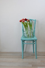vintage turquoise chair with pink tulips in glass vases 