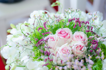 A bouquet of pink roses with pink cactus flowers, surrounded by white orchids.