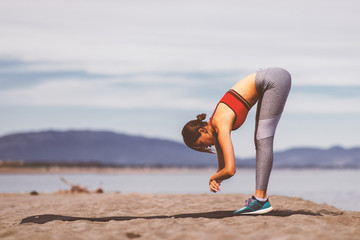 Young woman practicing yoga on the beach