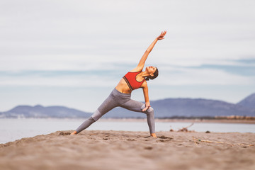 Young woman practicing yoga on the beach