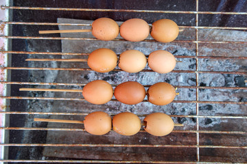 Thai street food, Special grilled eggs,  Steamed egg with seasonnings, Egg skewers on charcoal stove