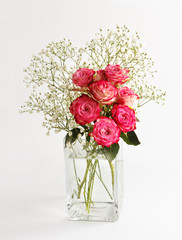 delicate bouquet with roses in a glass vase on a white background