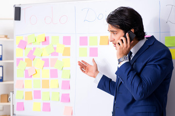 Young handsome employee in front of whiteboard with to-do list  