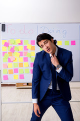 Young handsome employee in front of whiteboard with to-do list  