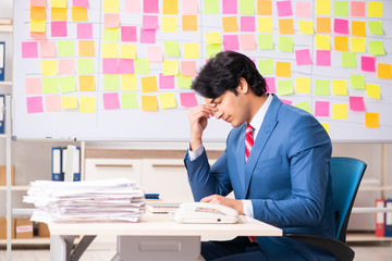 Young handsome employee with many conflicting priorities 