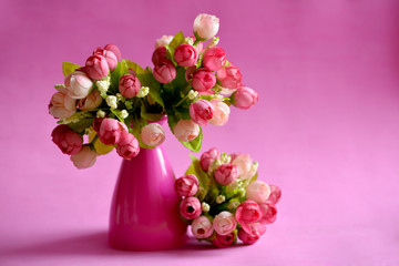 Pink vase with a bouquet of artificial flowers of roses