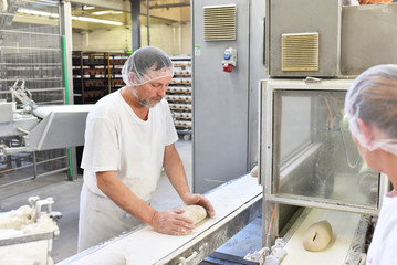 älterer Arbeiter am Fliessband einer Großbäckerei // older worker at the assembly line of a...