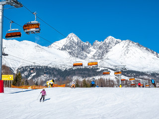 Chair lifter in ski resort with skiers and Tatry mountains in the back ground