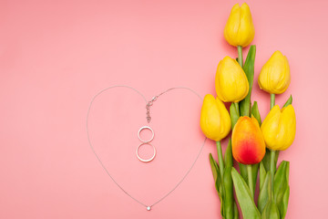 International Womens Day with flowers and heart shape necklace on pink background