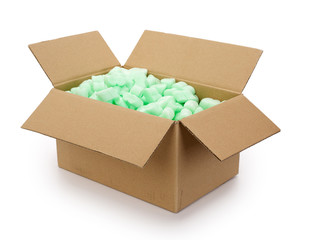 Brown corrugated cardboard moving box, filled with green styrofoam pellets or packing peanuts on white background. Contains clipping path.