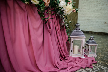 close up photo of a pink tablecloth on presidium table at a wedding and two lamps with candles on the floor