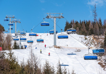 Ski resort, chair lift with skiers going up the hill. Tatry mountains, Tatrzanska Lomnica, Slovakia