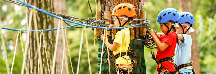 Children - a boy and a girl in the rope park pass obstacles. Brother and sister climb the rope road