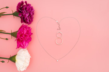 International Womens Day with flowers and heart shape necklace on pink background