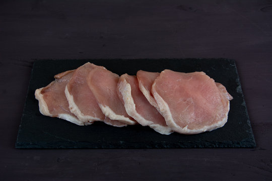 Horizontal Photo Of Whole Pork Tenderloin Raw Meat Is On A Black Slate Dish With Aromatic Herbs